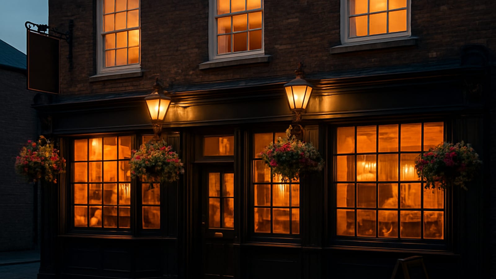 A traditional UK pub exterior at dusk with warm lighting and a welcoming atmosphere